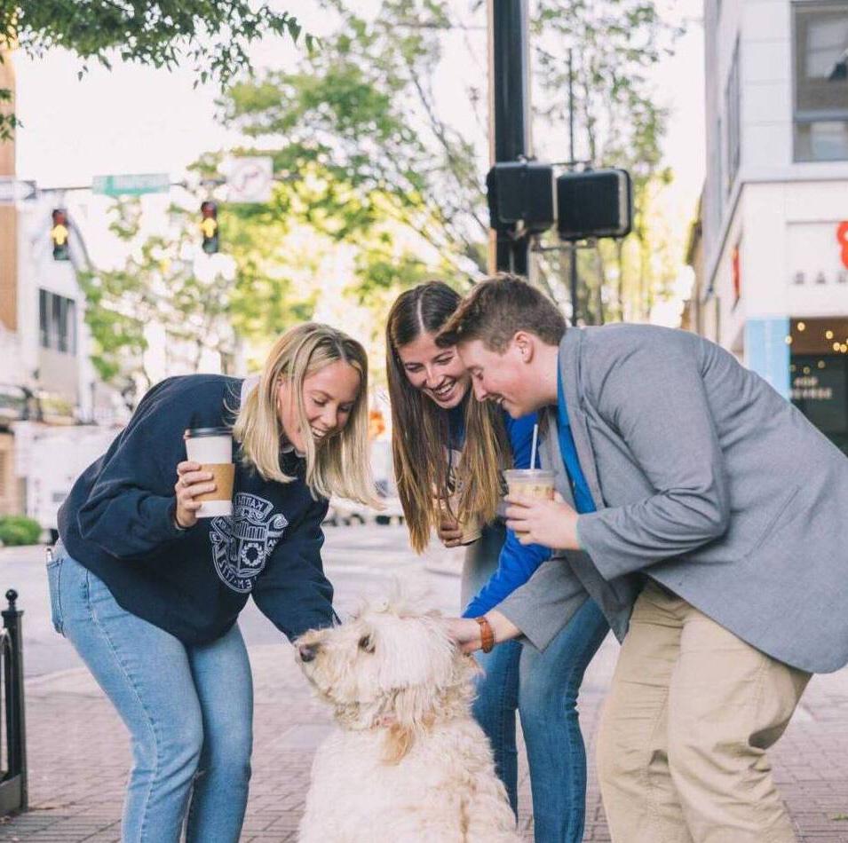 三名学生在温斯顿立博市中心抚摸一只狗
