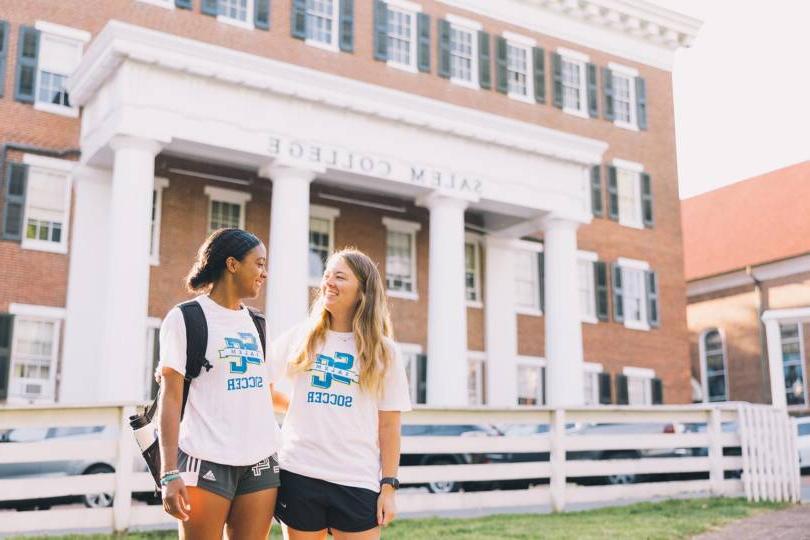 Two Salem College Students in Soccer shirts in front of Salem Building